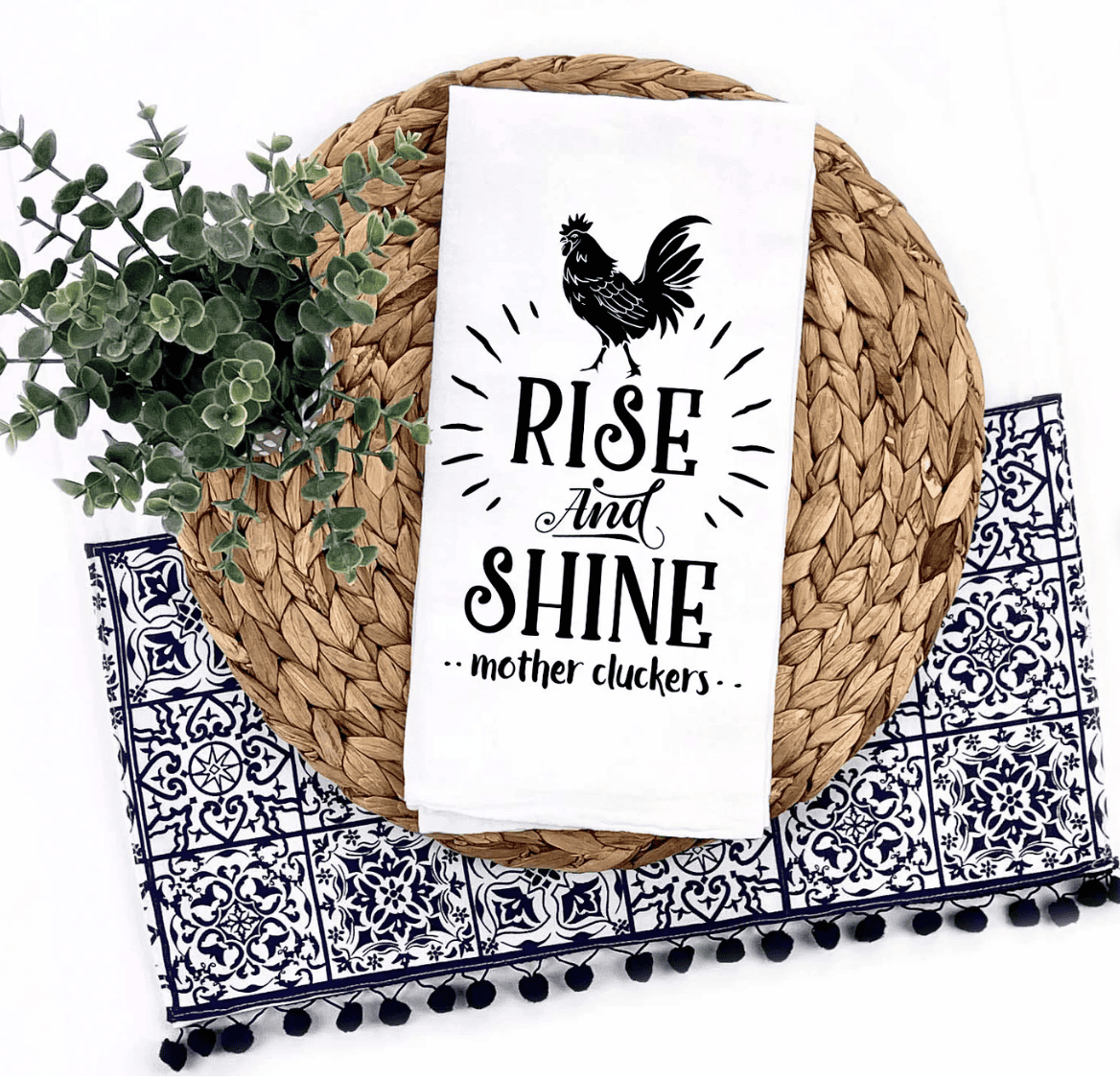 a white towel with a chicken on the front and the words, rise and shine mother clucker on the front